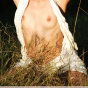 Blond girl with beautiful face in a white blouse shows her body outdoor.